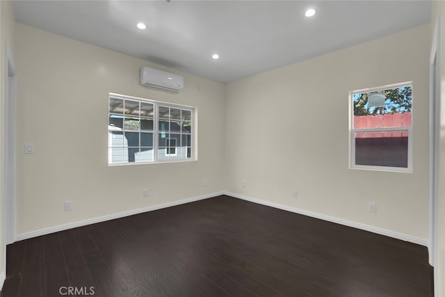 unfurnished room featuring a wall unit AC, wood finished floors, baseboards, and recessed lighting