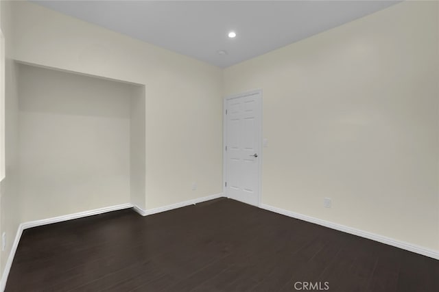 unfurnished room with dark wood finished floors, baseboards, and recessed lighting