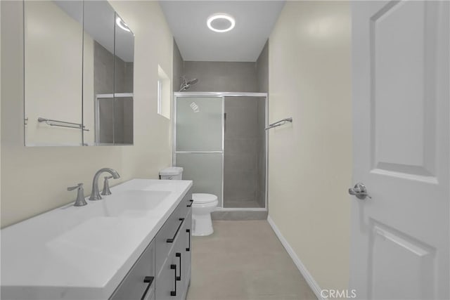 bathroom with a stall shower, toilet, vanity, and baseboards