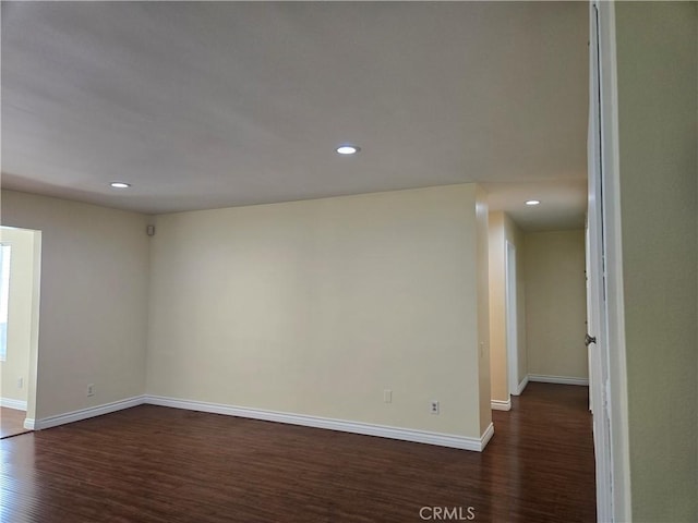 empty room featuring dark wood-style flooring, baseboards, and recessed lighting