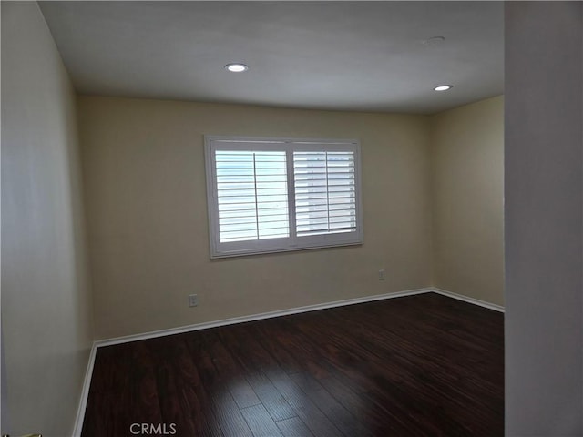 empty room with dark wood finished floors, baseboards, and recessed lighting
