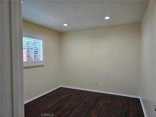 empty room with dark wood-style flooring, baseboards, and recessed lighting