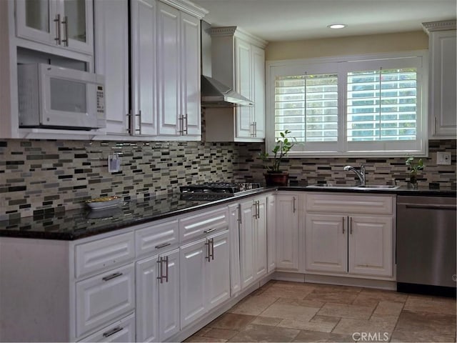 kitchen with appliances with stainless steel finishes, a sink, wall chimney exhaust hood, tasteful backsplash, and recessed lighting