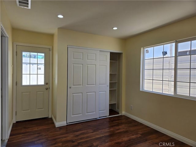 unfurnished bedroom featuring baseboards, dark wood-type flooring, a closet, and recessed lighting
