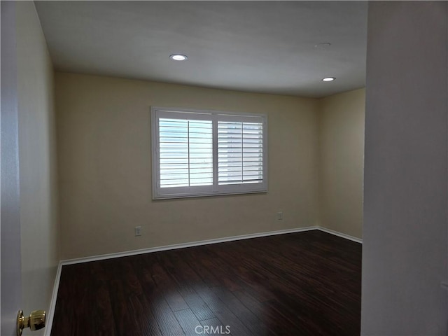 empty room featuring dark wood-type flooring, baseboards, and recessed lighting