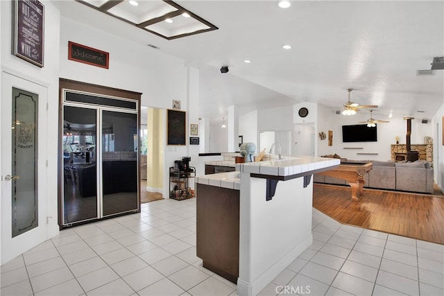 11020 Blue Jay Way, Oak Hills, CA 92344 - kitchen with tile countertops, high end black fridge, light tile patterned floors, open floor plan, and a ceiling fan