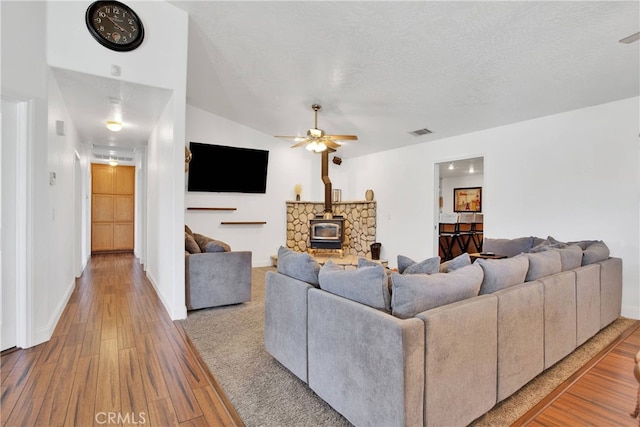11020 Blue Jay Way, Oak Hills, CA 92344 - living area with a wood stove, wood finished floors, ceiling fan, baseboards, and a textured ceiling