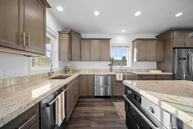 kitchen with stainless steel appliances, a sink, light stone counters, recessed lighting, and dark wood-style floors