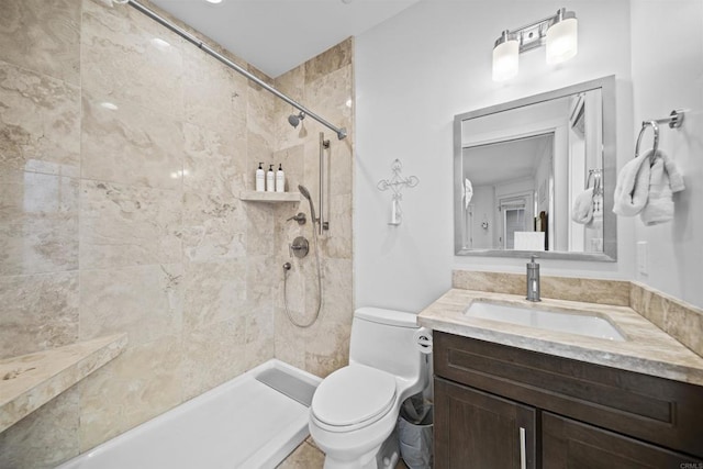 bathroom featuring toilet, a tile shower, and vanity