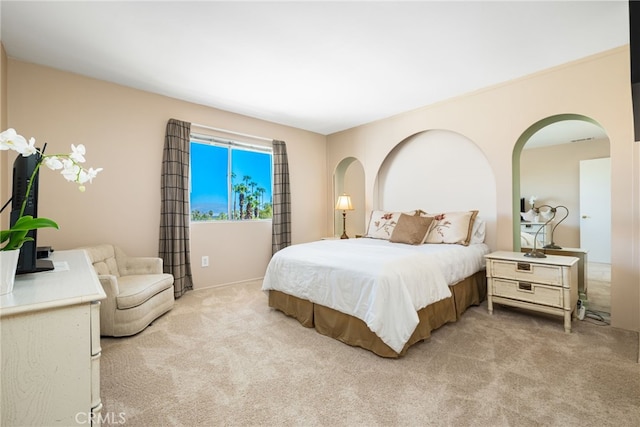 carpeted bedroom featuring arched walkways