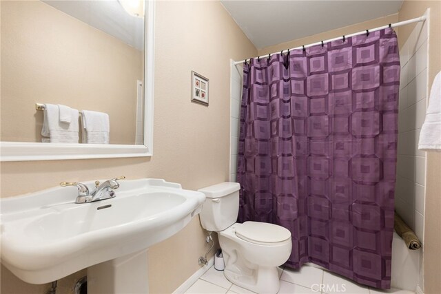 full bath with a shower with curtain, toilet, tile patterned floors, and a sink