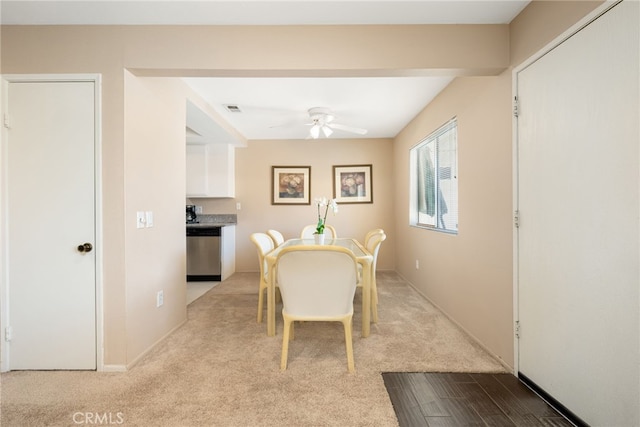 dining space featuring a ceiling fan and light carpet