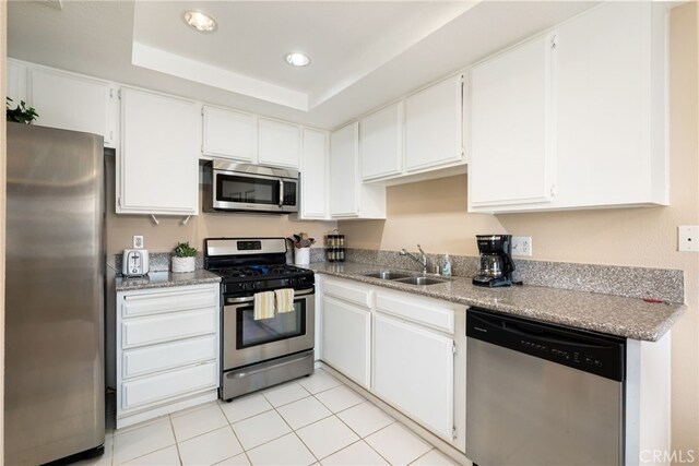 kitchen featuring appliances with stainless steel finishes, a sink, white cabinets, light tile patterned floors, and recessed lighting