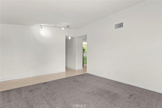 spare room with light carpet, track lighting, and baseboards