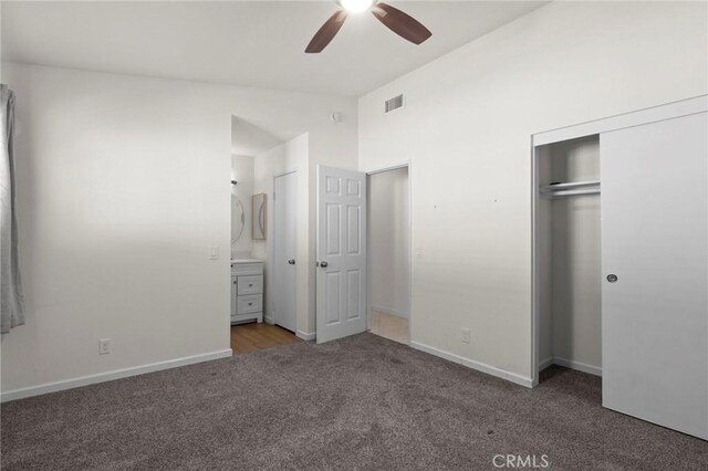 unfurnished bedroom with carpet, a closet, baseboards, lofted ceiling, and ensuite bath