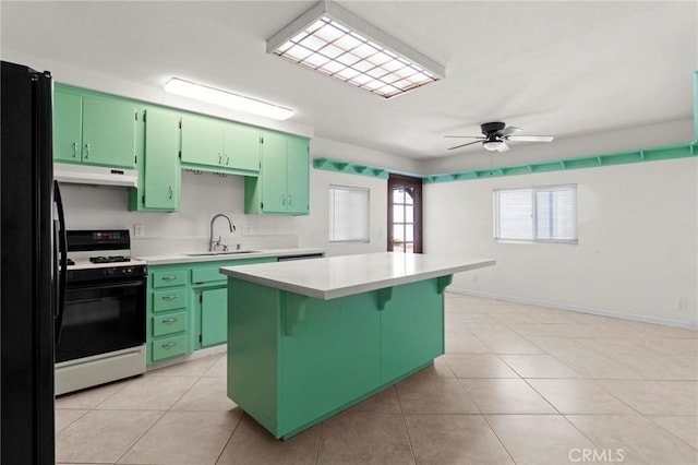 kitchen with white gas range, green cabinetry, a sink, and under cabinet range hood
