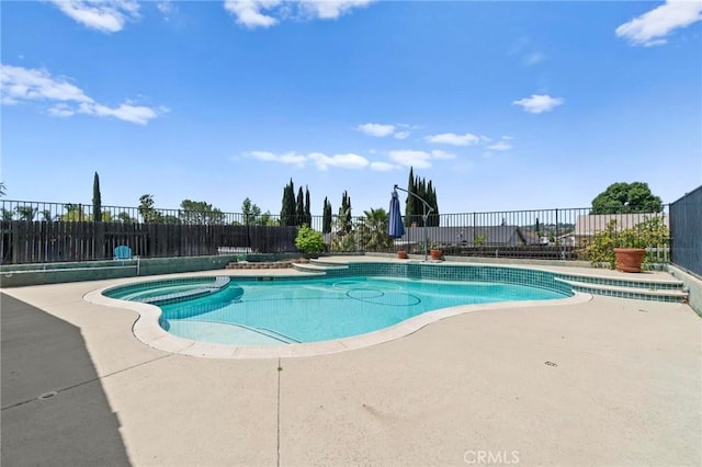 view of swimming pool with a patio, fence, and a pool with connected hot tub