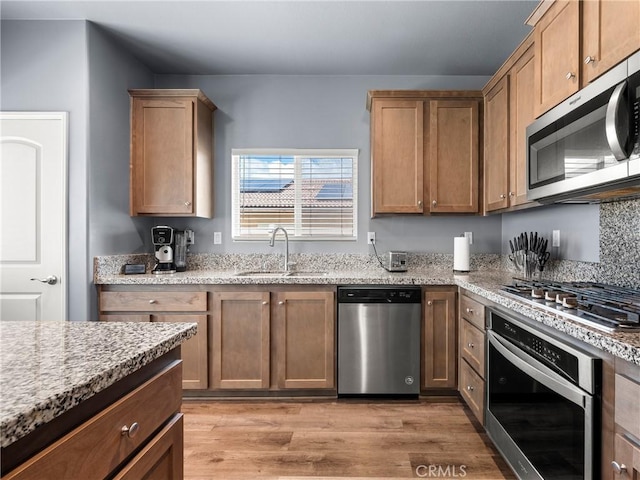 10630 Appaloosa Ave, Hesperia, CA 92345 - kitchen featuring appliances with stainless steel finishes, a sink, light wood-style floors, and light stone counters