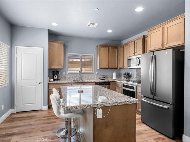 10630 Appaloosa Ave, Hesperia, CA 92345 - kitchen featuring appliances with stainless steel finishes, a center island, a sink, a breakfast bar area, and light wood-type flooring