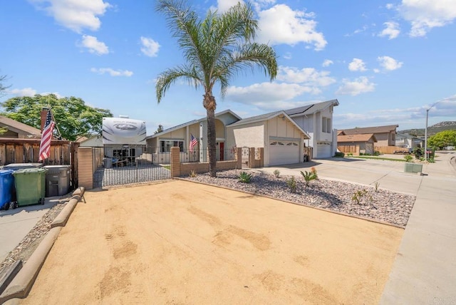 view of front of house with a gate, concrete driveway, board and batten siding, solar panels, and an attached garage