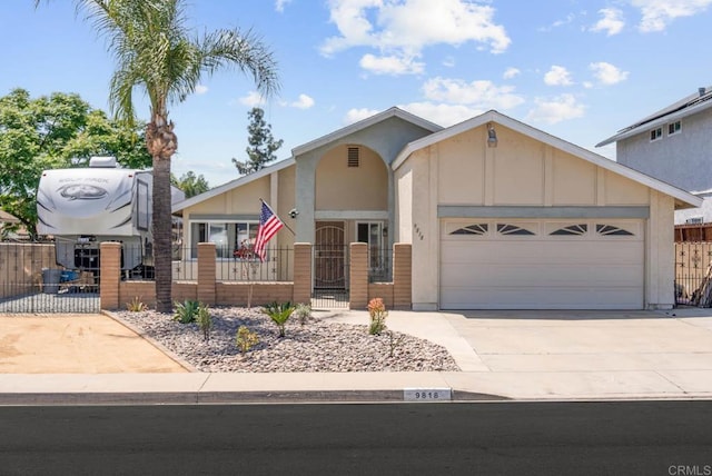 view of front of property featuring a fenced front yard, concrete driveway, an attached garage, and a gate