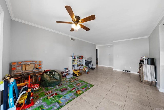 recreation room with crown molding, a ceiling fan, tile patterned flooring, and baseboards