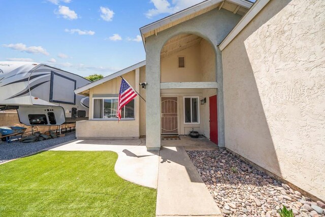 property entrance with stucco siding and a lawn