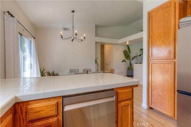 1918 Potter Rd, Chico, CA 95928 - kitchen with appliances with stainless steel finishes, light wood-type flooring, a chandelier, hanging light fixtures, and brown cabinetry