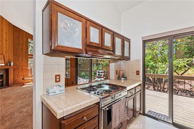 27657 Peninsula Dr, Lake Arrowhead, CA 92352 - kitchen featuring stainless steel electric range, tile counters, decorative backsplash, wooden walls, and under cabinet range hood