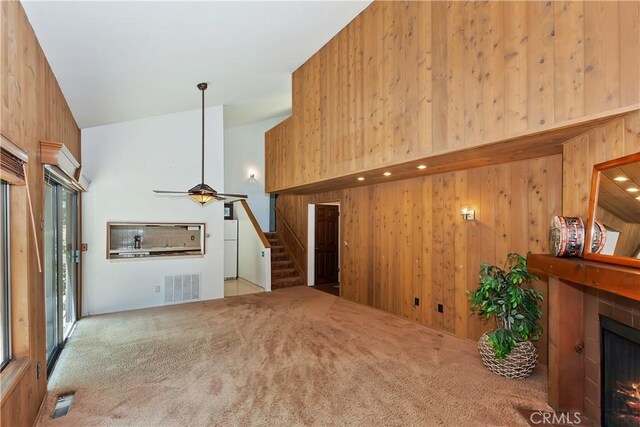 27657 Peninsula Dr, Lake Arrowhead, CA 92352 - unfurnished living room with a tile fireplace, wood walls, carpet flooring, stairs, and ceiling fan