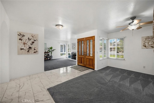 carpeted foyer entrance featuring marble finish floors, ceiling fan, and baseboards