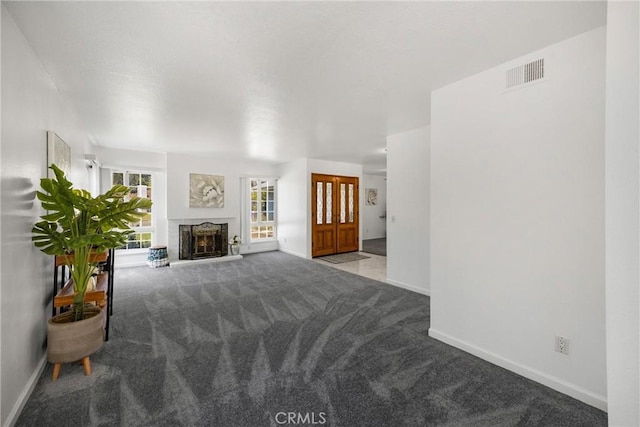 unfurnished living room featuring carpet floors, baseboards, and a fireplace with raised hearth