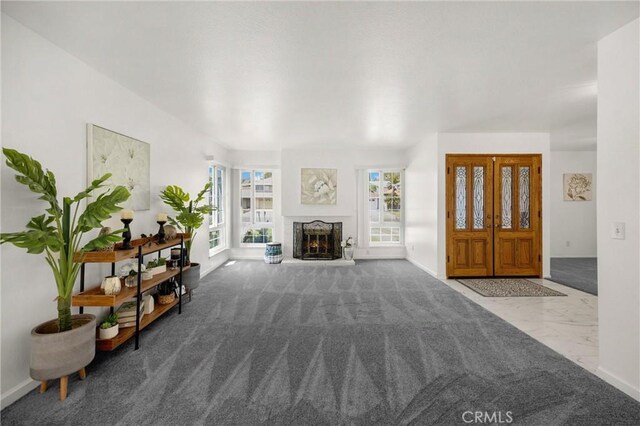 living room featuring baseboards, a lit fireplace, and marble finish flooring
