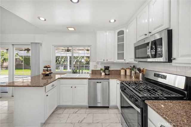 kitchen with stainless steel appliances, a sink, a peninsula, light marble finish floors, and white cabinets