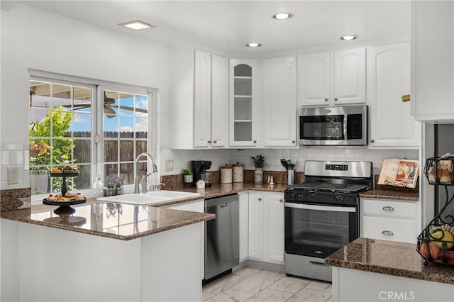 kitchen with stainless steel appliances, a sink, white cabinetry, dark stone counters, and recessed lighting