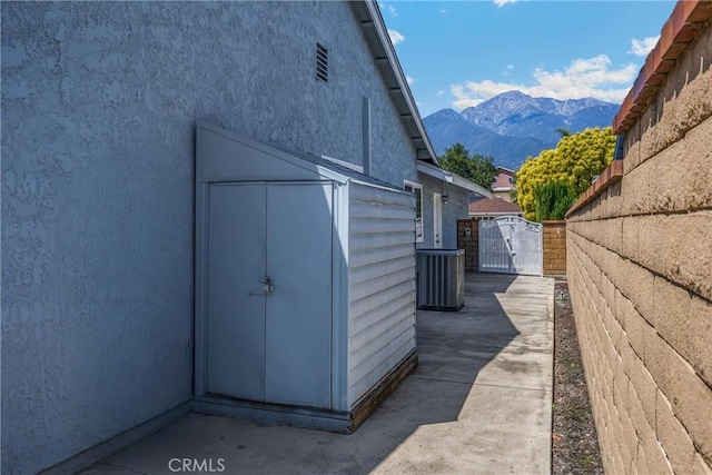view of shed with a gate, a mountain view, central AC unit, and fence