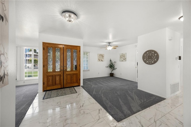 foyer entrance featuring marble look tiles, baseboards, and a ceiling fan