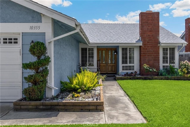 property entrance with french doors, a lawn, roof with shingles, a chimney, and a garage