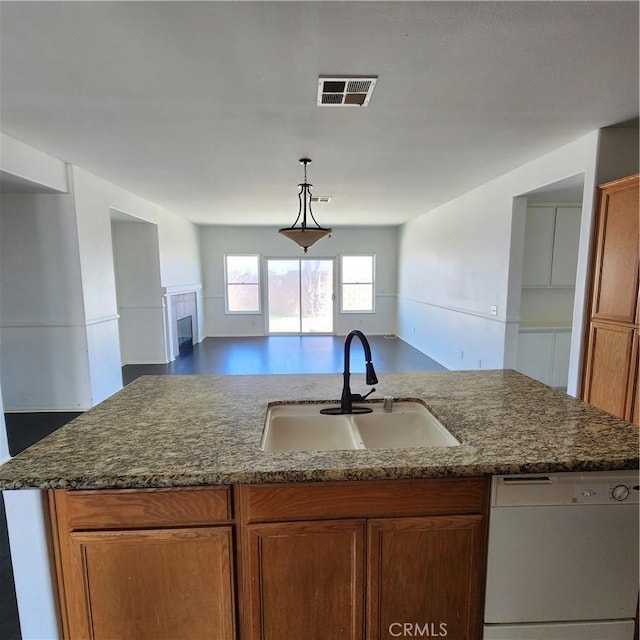 4542 Kalpesh Ct, Hemet, CA 92544 - kitchen featuring dishwasher, a sink, open floor plan, dark stone countertops, and brown cabinets