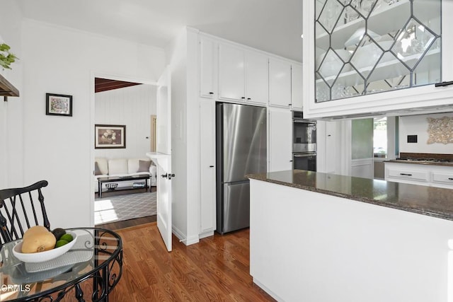 kitchen featuring stainless steel appliances, dark wood-style flooring, white cabinets, and dark stone counters