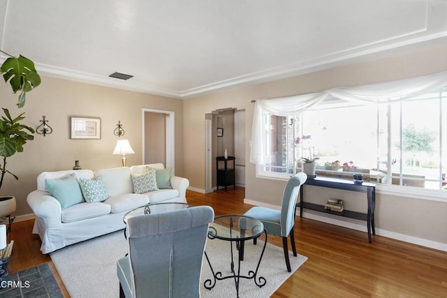living area with baseboards, wood finished floors, and ornamental molding