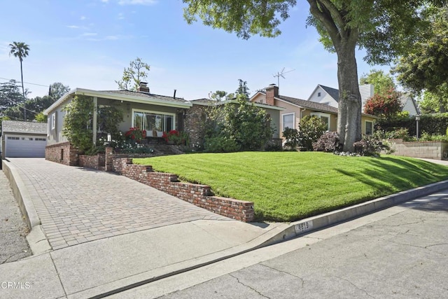 view of front facade featuring a front lawn, an outdoor structure, and brick siding
