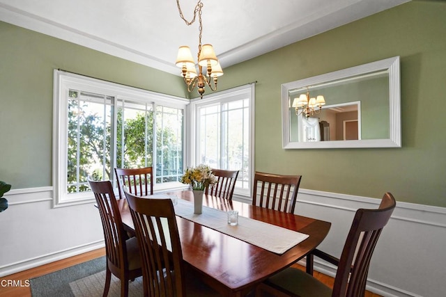 dining room featuring a chandelier, wood finished floors, and wainscoting