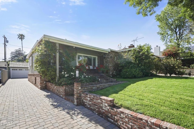 view of front of house featuring a garage, a front lawn, and an outbuilding