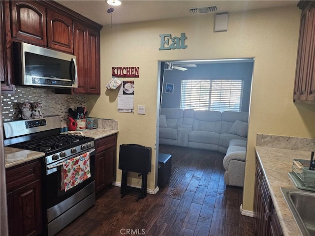 kitchen with stainless steel appliances, a ceiling fan, tasteful backsplash, light countertops, and dark wood-type flooring
