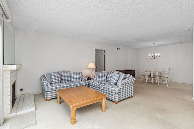 living area featuring a chandelier, carpet flooring, a textured ceiling, and a brick fireplace