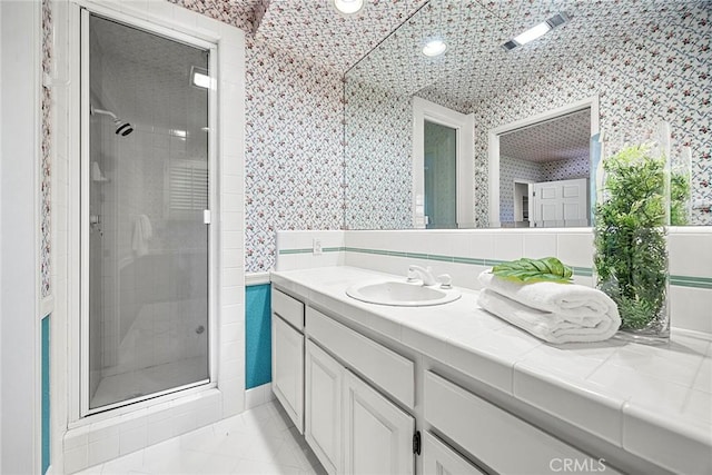 full bathroom with a shower stall, vanity, and wallpapered walls