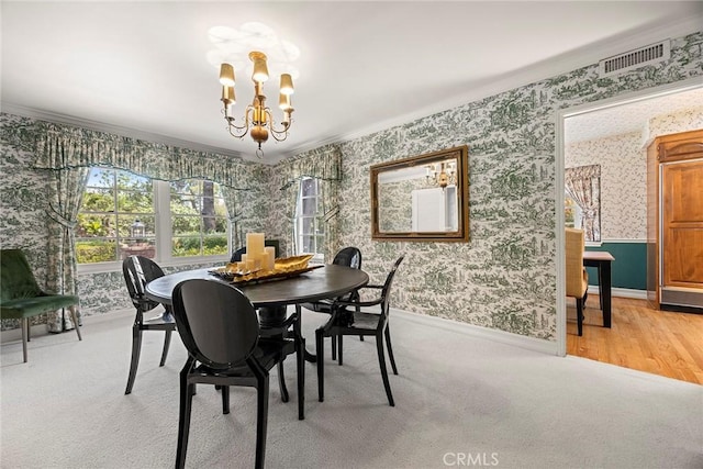 dining area featuring wallpapered walls, a chandelier, baseboards, light carpet, and ornamental molding