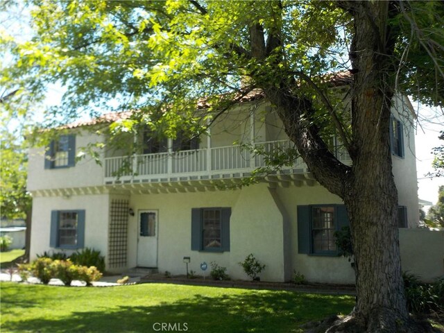 2698 Fremontia Dr, San Bernardino, CA 92404 - view of front of property with stucco siding, a balcony, and a front yard