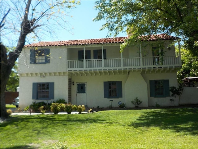 2698 Fremontia Dr, San Bernardino, CA 92404 - back of house featuring stucco siding, a tiled roof, a balcony, and a yard